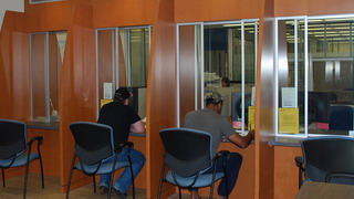 Deux personnes assises au comptoir d’accueil du Détachement de la GRC de Burnaby