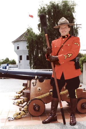 Officer in red serge next to a cannon 