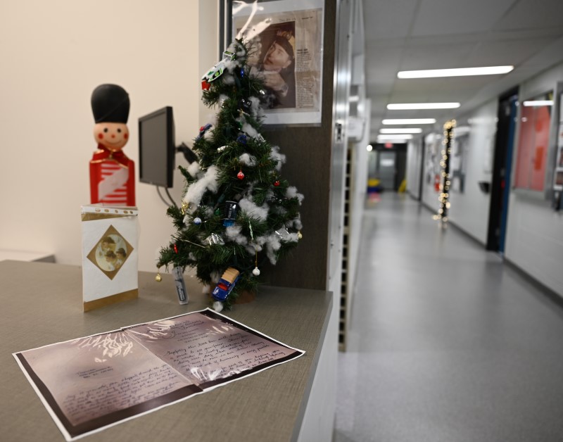 A small decorated Christmas tree sits inside on a counter inside the Burnaby detachment beside a printout of a  handwritten card
