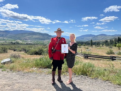 Sgt. Don Wriggesworth in red serge, standing next to new Canadian citizen, Anke Galardo, in Oliver, British Columbia.