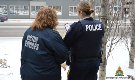  Photo d’un employé des Services aux victimes et d’un policier regardant ensemble un cahier. Ils tournent le dos à la caméra.