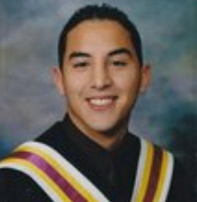 Photo of 17-year-old male with short dark hair, smiling, wearing a black graduation gown with white, yellow and maroon stripes.