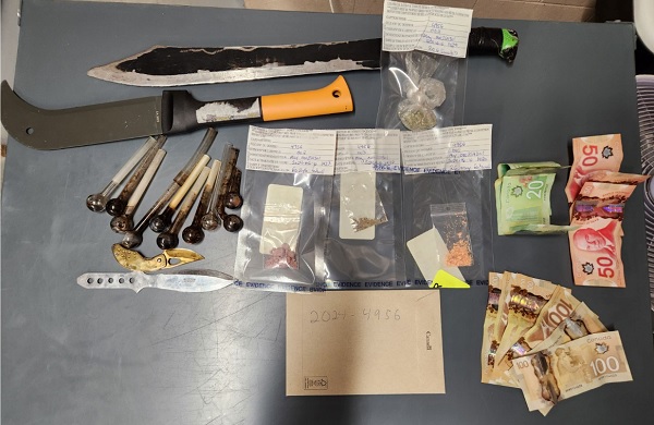 Display of weapons, drugs and drug paraphernelia layed out on table related to file 24-4956
