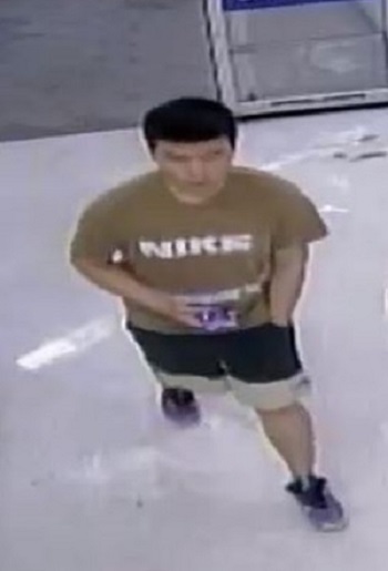 Un homme qui porte un tee-shirt havane ou brun arborant l’inscription « Nike » en lettres blanches sur le devant, un short foncé orné d’une bordure havane et des chaussures de sport