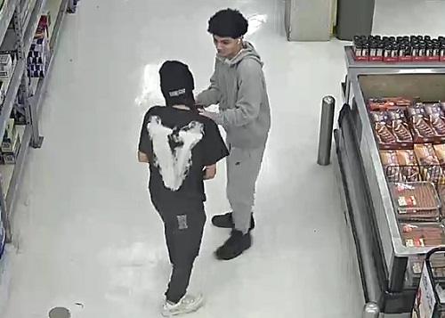 Vue de dos du suspect 2 qui parle au suspect 1 à l’intérieur du magasin