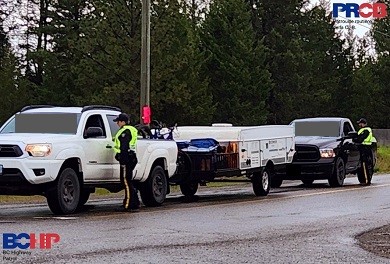 Deux agents de la Patrouille routière de la C. B. demandent à deux camionnettes de s’immobiliser à un barrage routier