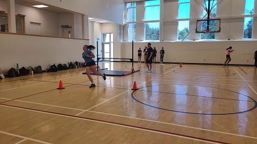 Jeune femme qui court entre des cônes dans un gymnase intérieur