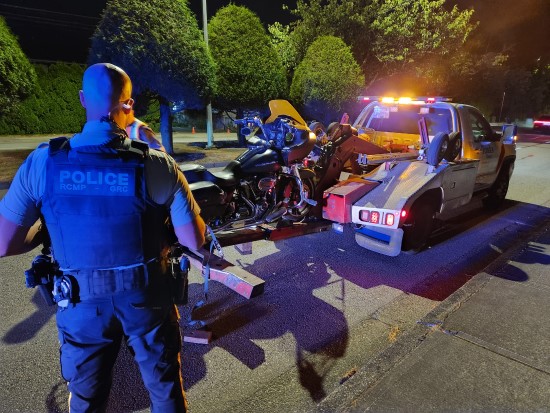 Richmond RCMP officer looks on as motorcycle is loaded onto tow truck