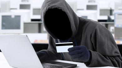 faceless man at a computer, holding a card