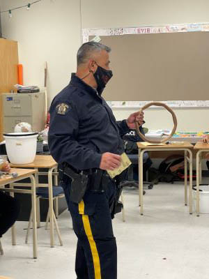 Photo of Cst Williams holding a circular drum frame in the classroom.