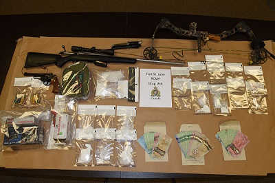Seized items including 1 rifle, 1 pistol, 1 compound bow, ammunition, various drugs in clear bags, and three packets of Canadian currency.