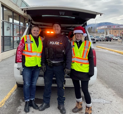 RCMP officer and two volunteers in front of police vehicle