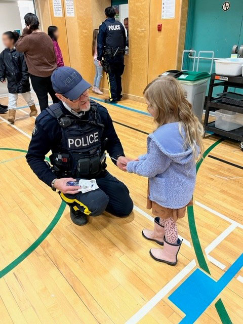 Constable Glenn Tjernagel giving a sticker to an elementary school student