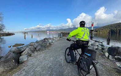 Un membre de la patrouille à bicyclette sur un sentier au bord de l’eau. 