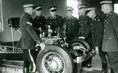 Sept policiers en uniforme autour d’une vieille voiture.