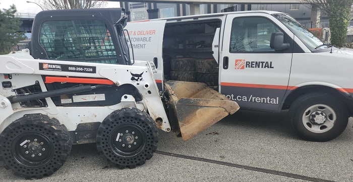 Chargeur à direction à glissement/bulldozer blanc et noir de la marque Bobcat garé dans une fourgonnette de location de Home Depot