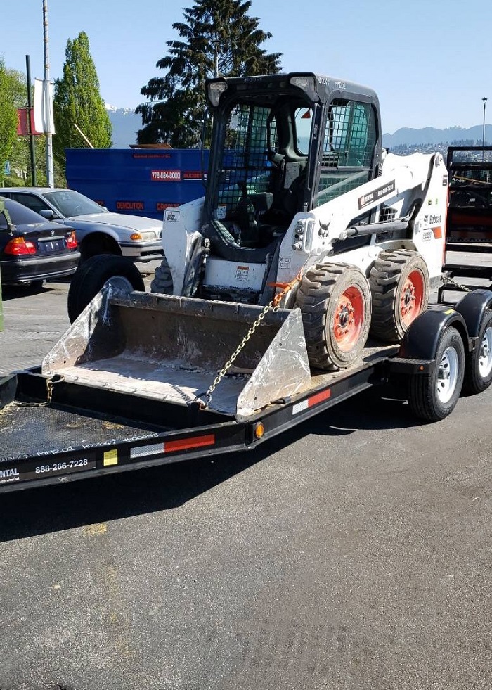 Bulldozer blanc, noir et orange de la marque Bobcat S510 sur une remorque