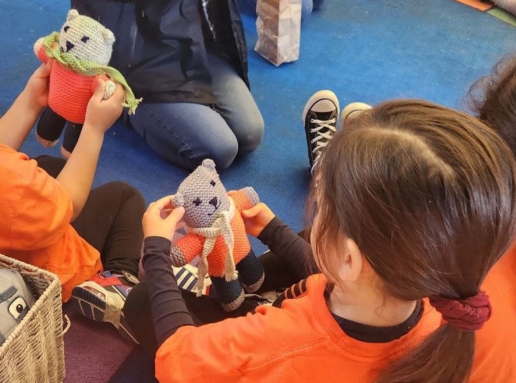 Photo of a little girl holdng a knitted teddy bear