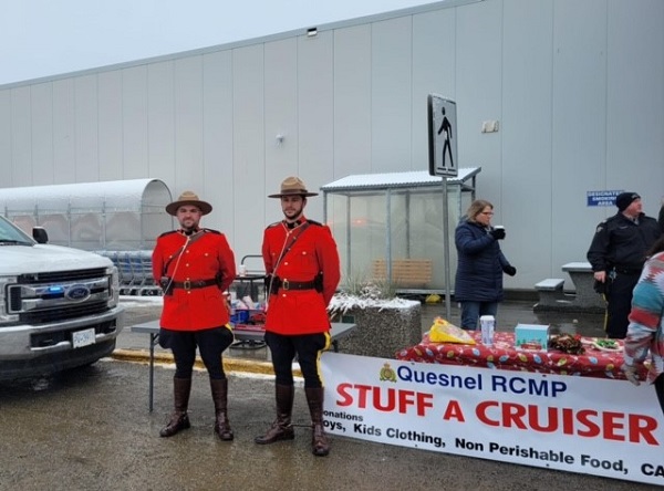 Two police officers in red serge stand by donation table with Stuff A Cruiser sign.