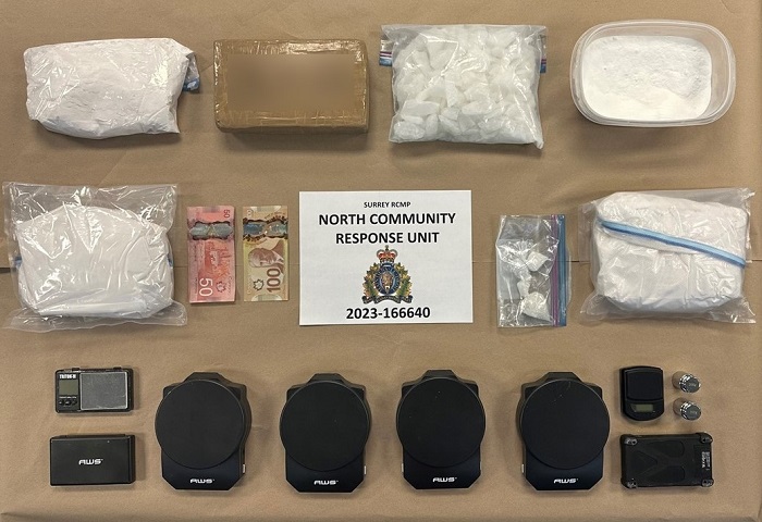 Photo of packages of controlled substances and buffing agents, digital scales, and cash. A sign in the middle of the displayed items reads "Surrey RCMP North Community Response Unit, 2023-166640".