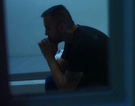 Still image of man sitting in cell from Shattering the Image video 