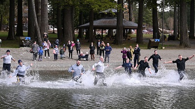 RCMP officers run into the cold water of Cultus Lake